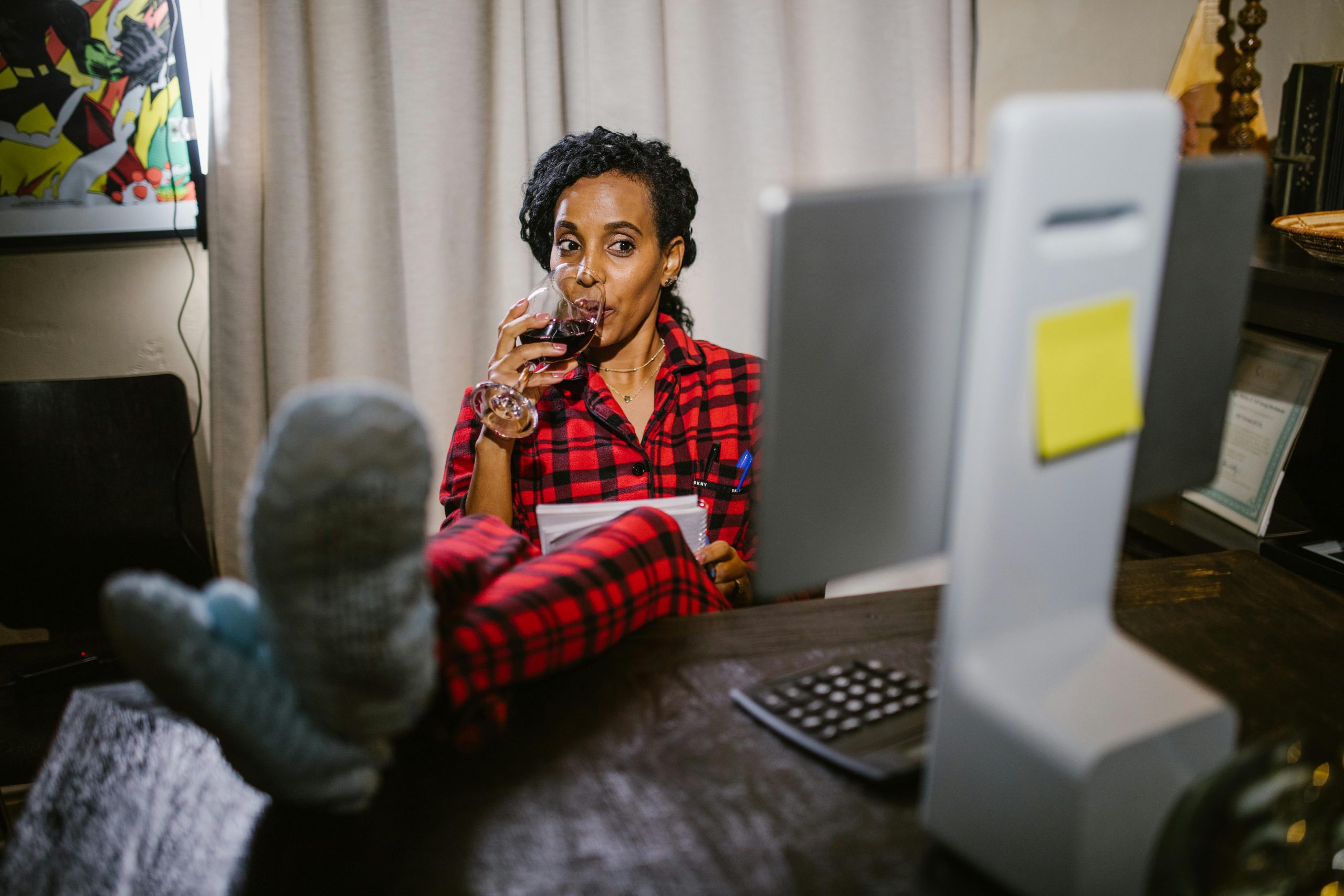 Female entrepreneur working late at night in pajamas with wine glass, focusing on laptop during weekend deep work session